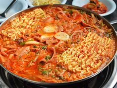 a pan filled with pasta and meat on top of a stove next to bowls of food