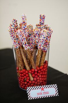 a glass filled with candy canes and sprinkles on top of a table