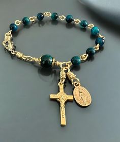 A new Catholic rosary bracelet.  Secures with a bronze lobster claw clasp. Length: 7-1/2" - For a tighter fit you can hook the clasp on to any of the links. Contact me prior to purchase if you need it larger and I'll be happy to add an extra link. Beads:  Blue tiger eye. 6mm For the Aves and an 8mm for the Pater bead. Medals: 3/4" Saint Benedict crucifix and a 1/2" oval Miraculous Medal with the Sacred and Immaculate hearts on the back.   Both are Italian made and beautifully detailed.  Gold fin Catholic Rosary Bracelet, Blue Tiger Eye, Blue Tiger, Saint Benedict, Catholic Rosary, Rosary Bracelet, Blue Tigers Eye, Rosary Catholic, Eye Beads