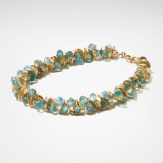 Gold & Stone Bracelet - Aqua apatite beads nestle between 22K gold vermeil disks in this bracelet with a delicate, feminine design and subtle sparkle. 14K gold-filled clasp. <br>Approximately 0.5W<br><br>The artist offers half sizes from 7- 8-1/2 long. Please indicate desired bracelet length below.<br><br>To find your correct size, measure your wrist over the bone, then add 1 to get bracelet length. Unique Faceted Yellow Gold Jewelry, Unique Spiral Yellow Gold Jewelry, Unique Yellow Gold Spiral Jewelry, Gold Single Strand Spiritual Bracelet, Faceted Yellow Gold Bracelet, Gold Briolette Bracelets With Natural Stones, Amber Gemstone Beads Rondelle Jewelry, Unique Single Strand Gold Jewelry, Unique Gold Single Strand Jewelry