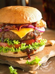 a cheeseburger with lettuce and tomato on a cutting board next to some fries