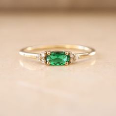 Introducing our Dainty Emerald Ring, a lovely choice for May birthdays or special moments. This minimalist gold ring features a lab-created emerald gemstone in an elegant oval cut. It's a delicate and charming option for an engagement or as a birthstone ring. The small emerald stone is accented with diamonds, adding a touch of sparkle. Celebrate love and life with this exquisite, understated gem. Key Features: * Gemstone: Chatam Lab Created Emerald Stone * Gemstone: Measurements: 1 Piece | Oval Cut 0.30ct * Side Gemstones: 100% Natural Diamonds * Side Gemstones Measurements: 6 Pieces | Round Cut 0.03ct * Material: High-Quality Solid Gold 14k ------CUSTOMIZATION------ ♥ Feel free to contact me for any other customization to your preferences. How to order: * Ordering is easy! Just use the Me Oval Gemstone Stackable Rings For Promise, Oval Gemstone Stackable Promise Rings, Elegant Stackable Rings With Oval Accent Stones, Elegant Stackable Oval Rings With Accent Stones, Dainty Oval Emerald Ring For Anniversary, Elegant Oval Stackable Rings With Accent Stones, Dainty Oval Solitaire Emerald Ring, Elegant Oval Stackable Rings With Center Stone, Dainty Oval Diamond Ring With Accent Stones