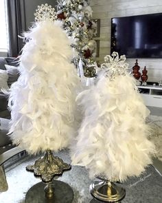 two white feather lamps sitting on top of a table in front of a christmas tree