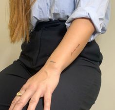 a woman with a tattoo on her left arm is sitting down and holding onto her leg