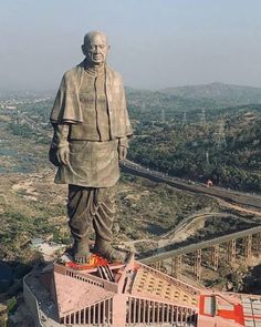 a large statue stands on top of a hill