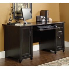 a desk with a computer on top of it in front of a mirror and rug