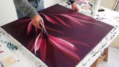 a man is painting an abstract flower on a piece of art with acrylic paint