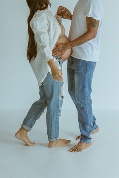 a man and woman standing next to each other in front of a white wall with their hands together