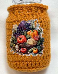 a crocheted jar with a painting of fruits and vegetables on it's lid