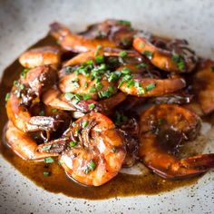 a white plate topped with shrimp covered in sauce and garnished with parsley