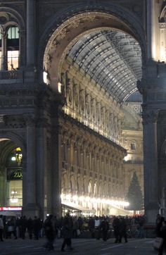 people are walking around in the middle of a building with an arched ceiling and many windows