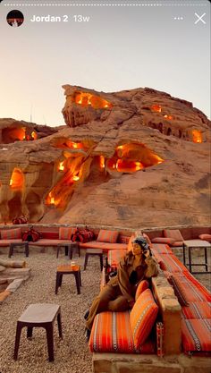 a woman sitting on top of a couch in front of a rock formation with lights