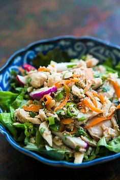 a blue bowl filled with salad on top of a wooden table