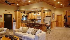 a living room filled with furniture next to a kitchen and dining room table on top of a carpeted floor