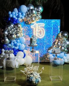 a table topped with balloons and vases filled with blue and white flowers on top of a green field