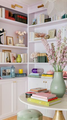 a vase filled with flowers sitting on top of a table next to a book shelf