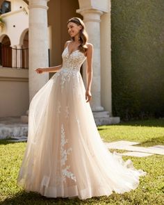 a woman in a wedding dress standing on the grass with her hand out and looking back