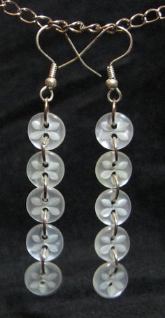 three clear glass beads hanging from a chain on a black background with a silver clasp