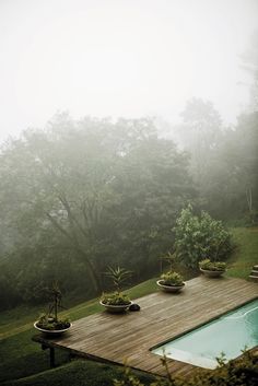 a wooden deck next to a pool surrounded by trees