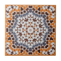 an orange and white tile with blue, brown and white designs on the bottom half