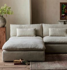 a white couch sitting on top of a wooden floor next to a vase filled with flowers