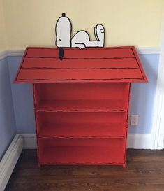 a red bookcase with a cartoon dog on top