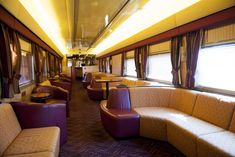 the inside of a train car with couches and tables on each side, along with windows