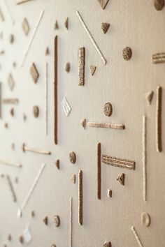 the wall is made up of different types of pins and screws on white paper