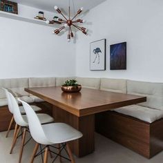 a dining room table with white chairs and a wooden bench in front of the table