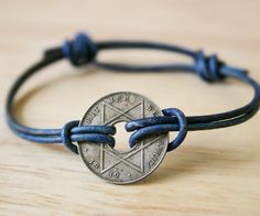 a bracelet with a coin on it sitting on top of a wooden table