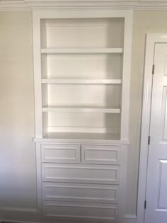 a white bookcase in the corner of a room with two doors and a rug on the floor