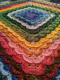 a multicolored crocheted blanket on top of a table