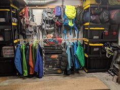 there are many coats and jackets hanging on the rack in this garage with storage bins