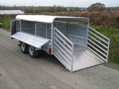 the trailer is parked on the side of the road next to some grass and bushes