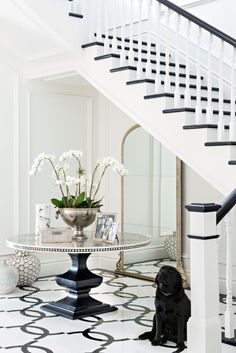 a black and white floor with flowers in a vase next to a mirror on the wall