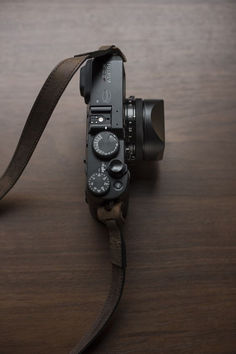 a camera on a wooden table with a leather strap