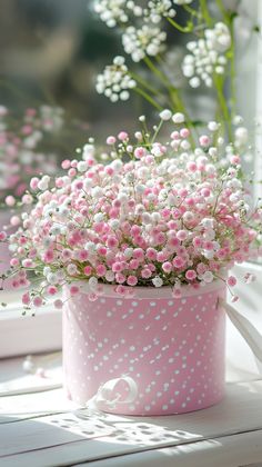 pink and white flowers are in a polka dot pot on a window sill,