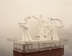 four statues are standing on the edge of a body of water