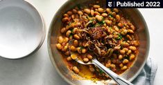 a bowl filled with beans and onions next to a spoon