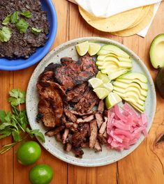 a plate with meat, avocado and other foods on it