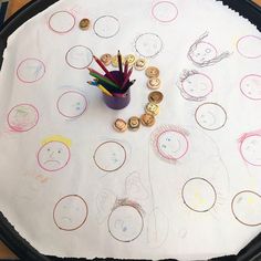 a child's drawing is shown on the table with pencils and coins next to it