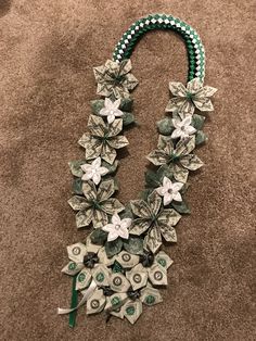 a necklace made out of dollar bills and flowers on top of a carpeted floor