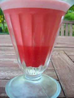 a glass filled with liquid sitting on top of a wooden table