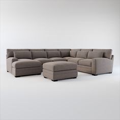 a large sectional couch with ottoman and footstool in front of a white wall