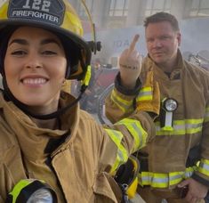 a woman in a fireman's uniform giving the peace sign