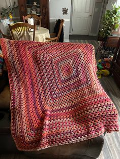 a crocheted blanket sitting on top of a leather chair in a living room