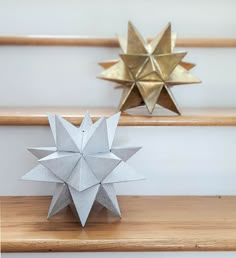 two origami stars sitting on top of a wooden shelf