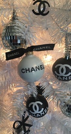 chanel ornament ornaments hanging on a white christmas tree with black and silver decorations