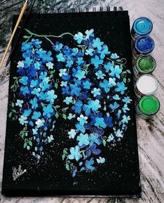 a painting with blue flowers on it next to paint brushes