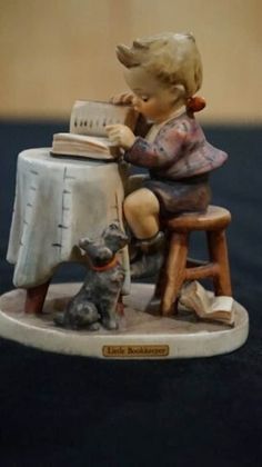 "The Hummel Little Bookkeeper is a figurine of a boy reading a book at a table. The figurine was designed by Arthur Moeller and stands 4.75\" tall. It was made in West Germany by Goebel. It is in mint condition" Boy Reading, Dozen Red Roses, Goebel Hummel, Red Rose Bouquet, Hummel Figurines, Jumping For Joy, Sleigh Ride, Reading A Book, God Bless America